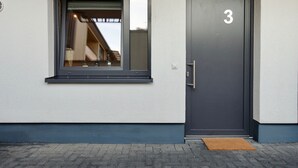 En moderne bygning med et stort vindue og en mørk dør med nummer 3.