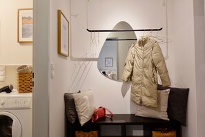 A laundry area with a washing machine, a drying rack, and a mirror reflecting the room.