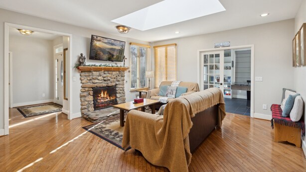 A living room with a stone fireplace, a sofa, a coffee table, and a skylight.