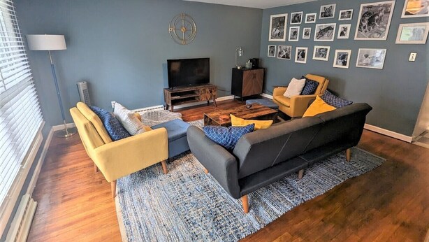 A living room with a sofa, armchairs, a coffee table, and a TV. - Relax at Moon Dogs Getaway! (Erie)