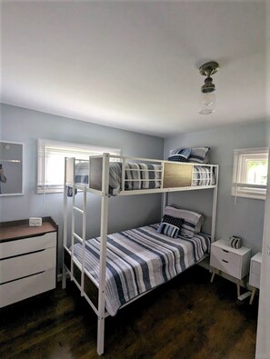 Une chambre avec un lit superposé, un bureau et une petite table de chevet.