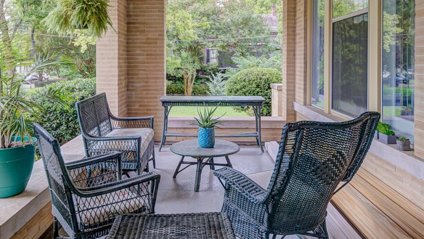 A covered patio with wicker furniture, a hanging light fixture, and a view of the garden. - Oak Hall Mansion and Boutique Hotel (Vicksburg)