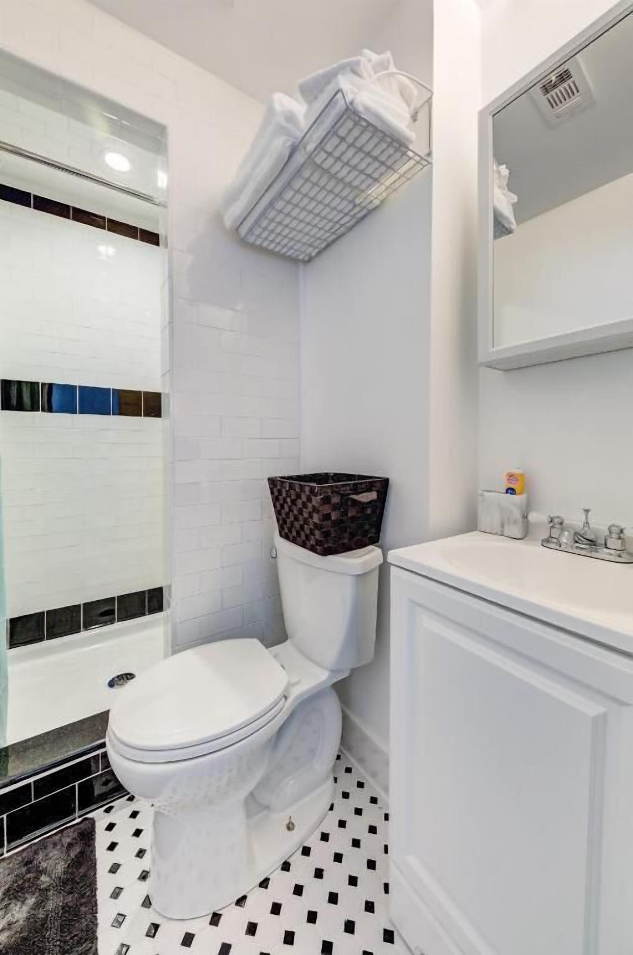 Een badkamer met een wit toilet, een wastafel en een spiegel.
