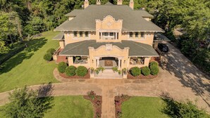 A large, two-story house with a symmetrical facade, a central entrance with a decorative archway, and a driveway leading to a garage. - Oak Hall Mansion and Boutique Hotel (Vicksburg)