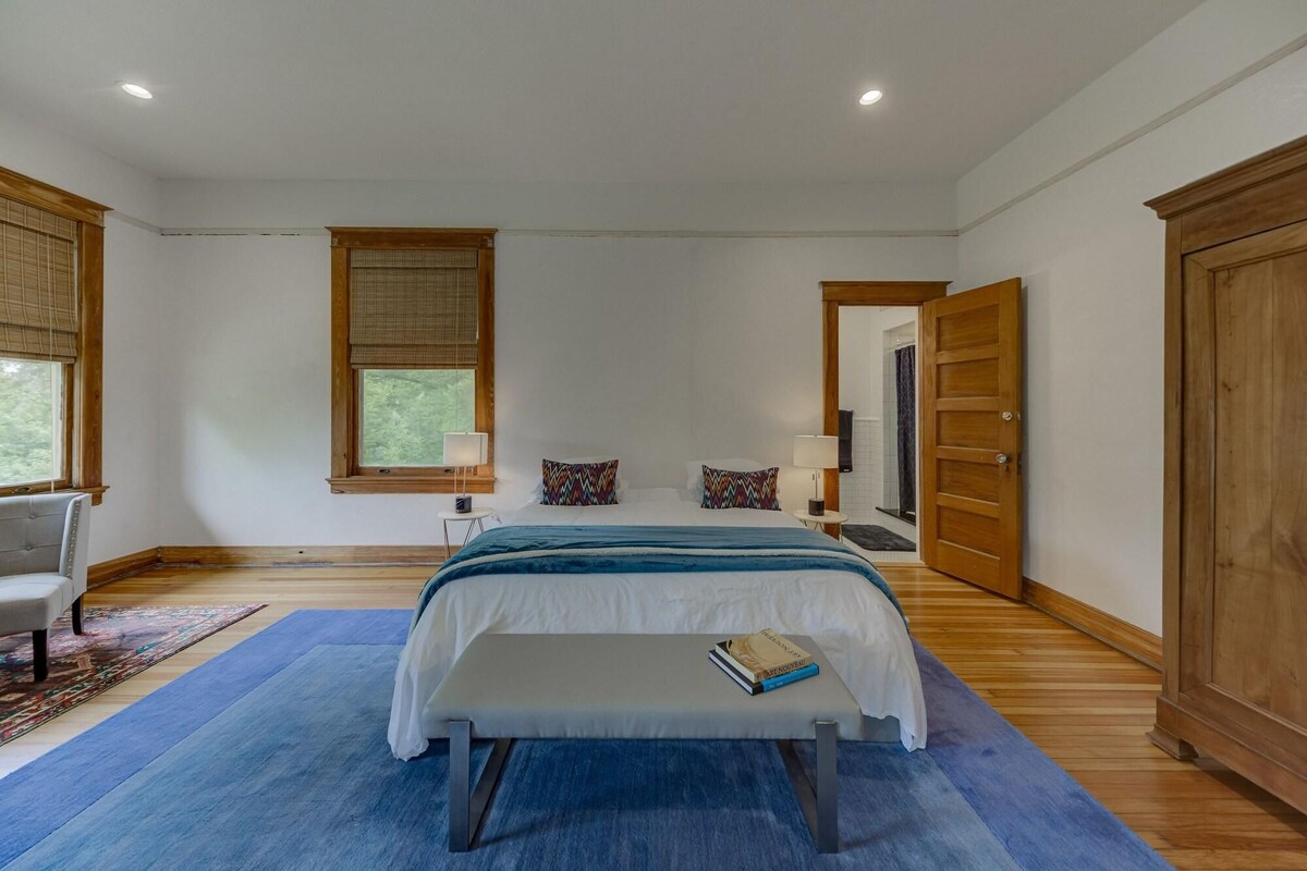 A bedroom with a bed, bedside tables, a chair, a window, and a wardrobe.