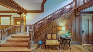 A grand staircase with wooden railings and a bench at the bottom. - Oak Hall Mansion and Boutique Hotel (Vicksburg)
