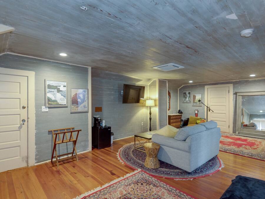 A living room with a grey sofa, wooden flooring, and a large mirror.
