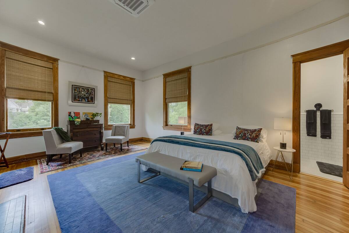 A spacious bedroom with a large bed, a bench, a dresser, and a chair.