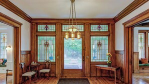A traditional interior with wooden paneling, a chandelier, and stained glass windows. - Oak Hall Mansion and Boutique Hotel (Vicksburg)