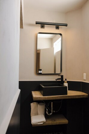 Ein modernes Badezimmer mit einem schwarzen Waschbecken, einem Spiegel und einem Handtuchhalter.