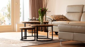 A modern living room with a sofa, two coffee tables, and a vase with flowers.