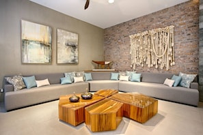 A modern living room with a sectional sofa, a wooden coffee table, and abstract paintings on the wall.