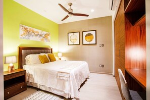 Un dormitorio con una cama, mesitas de noche, ventilador de techo, obras de arte y un armario de madera.