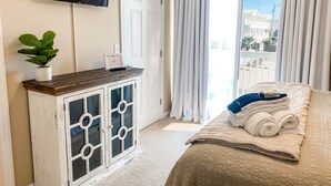 Une chambre à coucher avec un lit, une commode, un téléviseur et une vue sur l’extérieur.