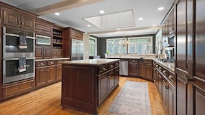 Una cocina amplia con gabinetes de madera oscura, electrodomésticos de acero inoxidable y una isla grande.