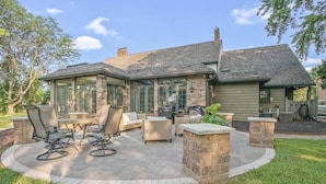 Una casa con patio, mobiliario exterior y una chimenea de piedra.
