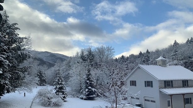 Ett snötäckt landskap med ett hus och berg i bakgrunden.