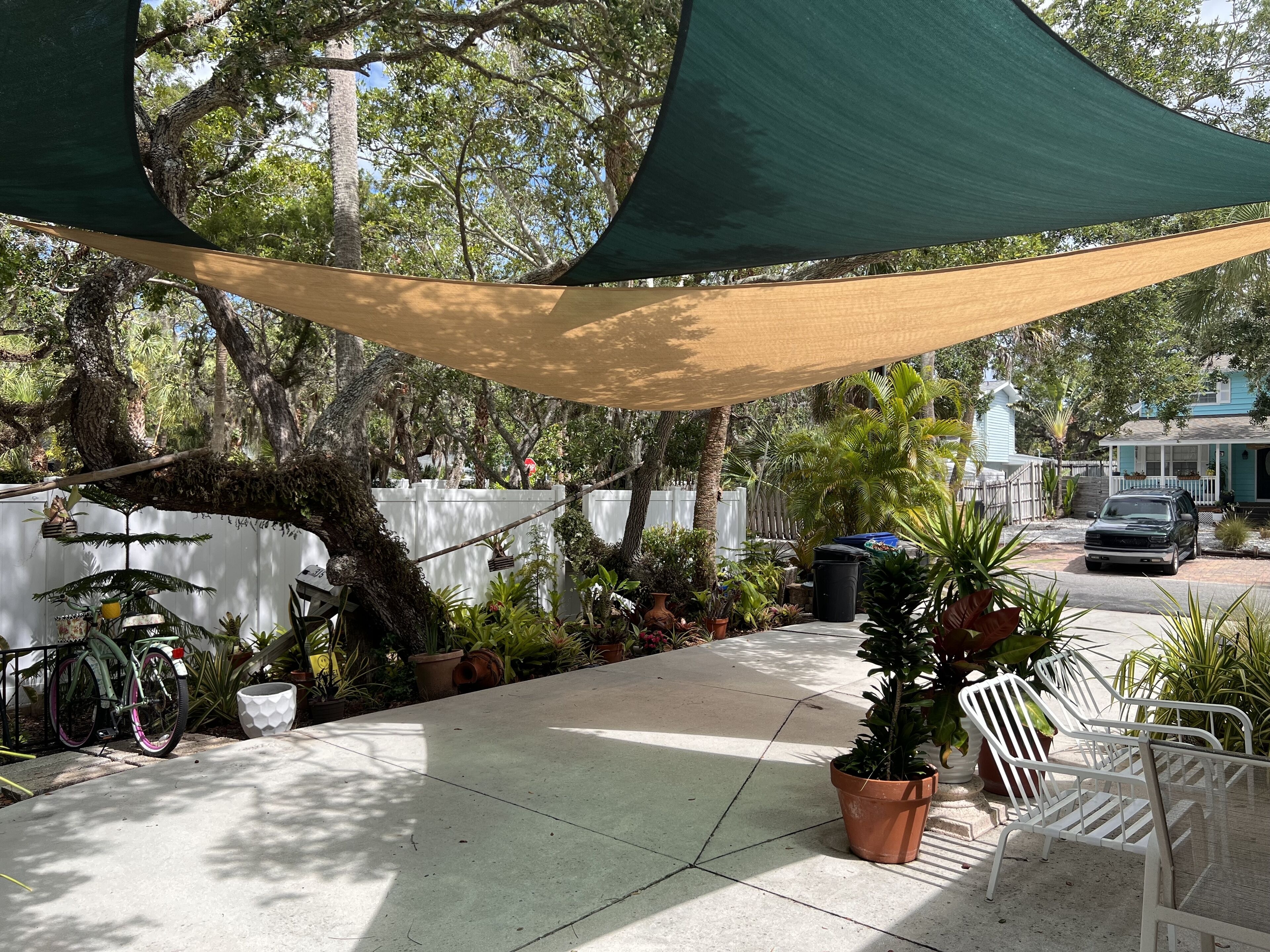 A patio with a bicycle, potted plants, and outdoor furniture under a shade structure.