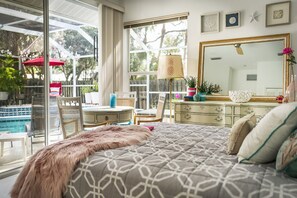 A bedroom with a large bed, a dresser, a mirror, and a view of a pool. - :: Villa Oasis – Elegant & Peaceful Pool Retreat in Siesta Key :: (Siesta Key)