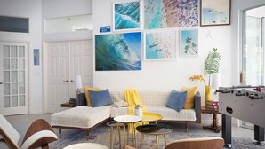 A living room with a sofa, armchairs, a coffee table, and a foosball table. There are framed pictures on the wall and a plant on a side table. - :: Villa Oasis – Elegant & Peaceful Pool Retreat in Siesta Key :: (Siesta Key)
