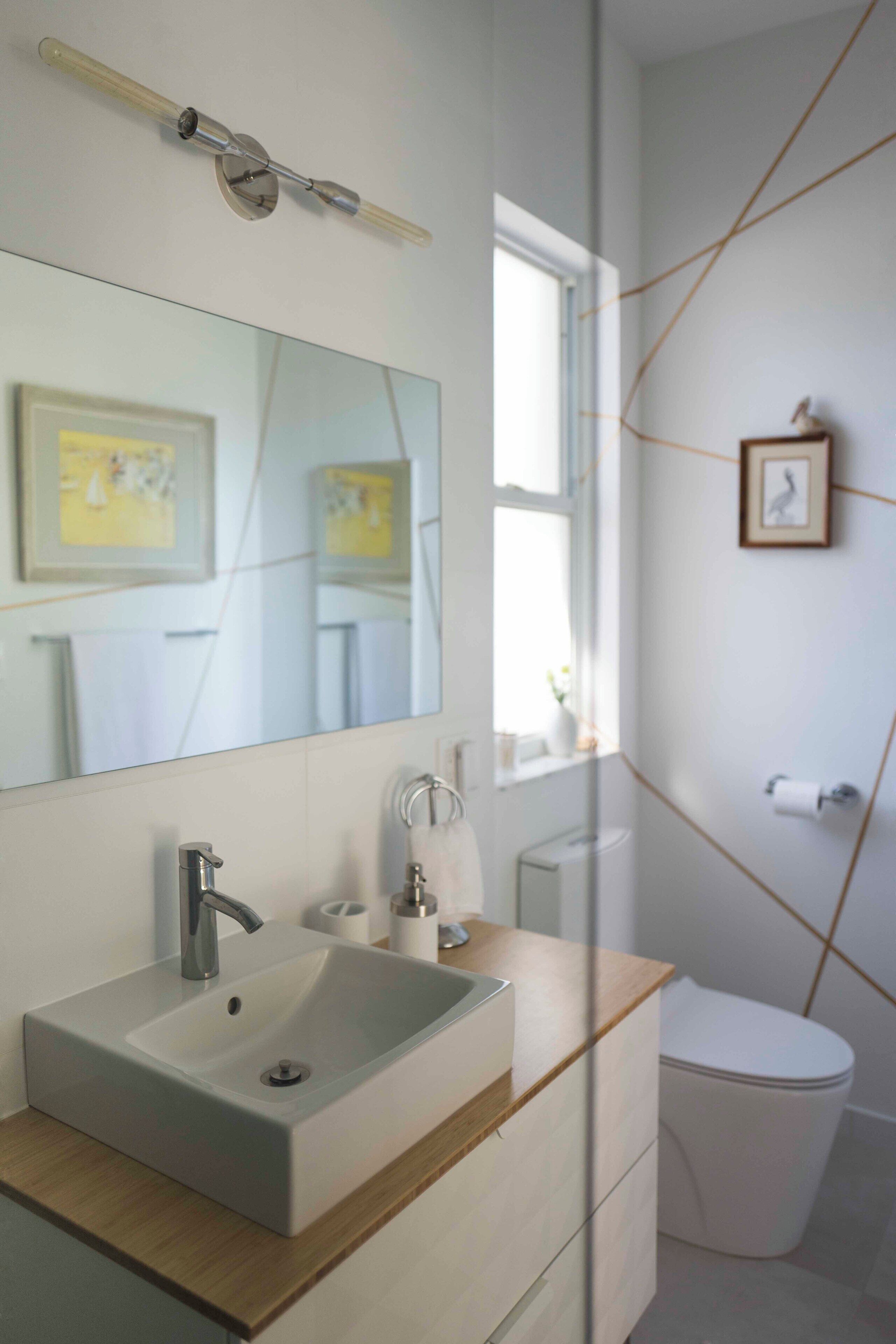 Une salle de bain moderne avec un grand miroir, un lavabo et des toilettes.
