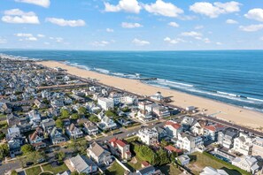 An aerial view of a coastal residential area with houses, a beach, and the ocean.