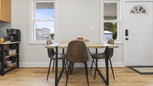 Un espace repas comprenant une table et des chaises, une machine à café et une vue sur l’extérieur par une fenêtre.