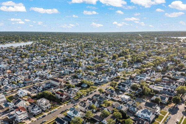 An aerial view of a residential area with houses, streets, and a water body in the background.
