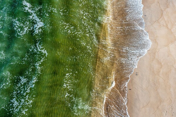 An aerial view of a beach with clear demarcation between the water and the sand.