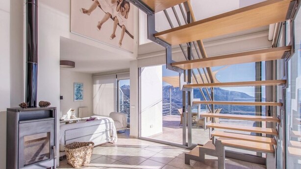 Un dormitorio moderno con una cama grande, una chimenea y un balcón con vistas a las montañas.