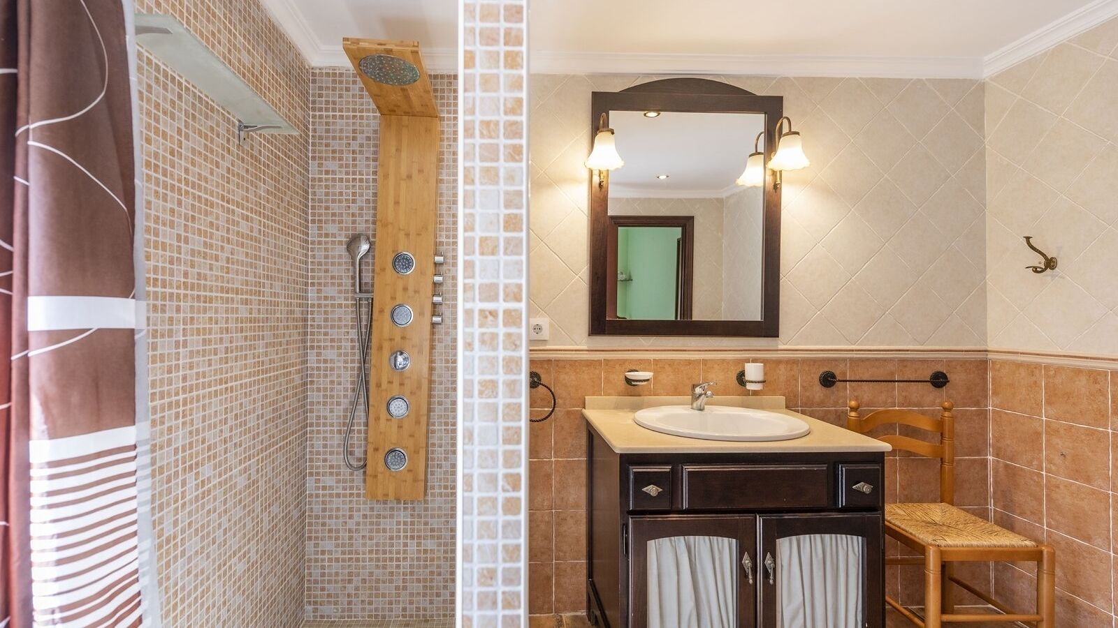 Een badkamer met een douche, een wastafel en een spiegel.