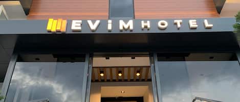 The exterior of the Evimhotel with a modern design, featuring a prominent entrance with steps and a glass facade.