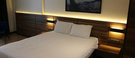 Una cama bien tendida con sábanas blancas, cabecera de madera y aire acondicionado de pared.