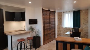 A modern kitchen with a wooden island, black cabinets, and a TV mounted on the wall.