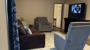 Ein Wohnzimmer mit grauem Sofa, grauem Sessel und Fernseher auf einem Schrank.