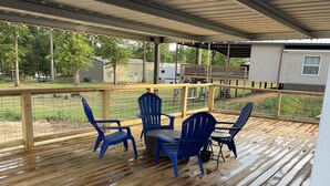 Eine überdachte Terrasse mit Holzboden und blauen Adirondack-Stühlen.