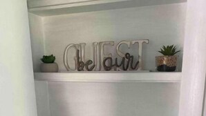 Une étagère blanche sur laquelle est inscrit le mot « BEAUTÉ », une petite plante et une sculpture en bois représentant un ours.