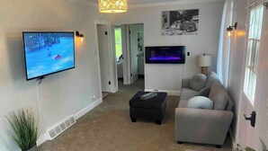 Un salon équipé d’un téléviseur à écran plat, d’une cheminée, d’un canapé et d’un ventilateur de plafond.
