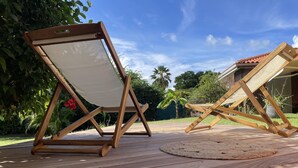 Twee houten ligstoelen met canvas rugleuningen op een houten terras.