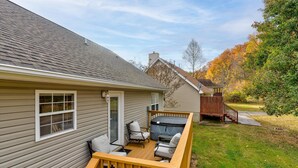 Una terraza con mobiliario exterior, un jacuzzi y una escalera de madera que lleva a una casa.