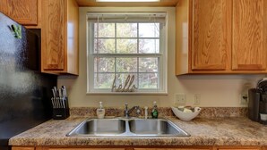 Una cocina con armarios de madera, un lavamanos doble y una ventana con un letrero que dice 'hello'.