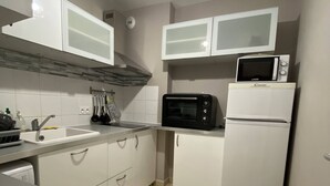 A compact kitchen with white cabinets, a microwave, a toaster oven, and a hanging light fixture. - Apartment between lake and sea amidst vineyards (Peret)