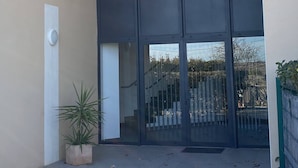 A modern building with large glass doors and a small potted plant on the ground. - Apartment between lake and sea amidst vineyards (Peret)
