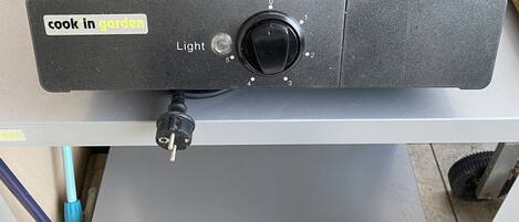 Un aparato de cocina portátil con una perilla de control y una etiqueta que dice 'cocinar en el jardín'.