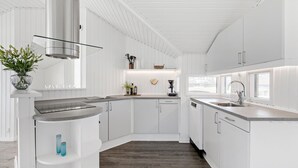 Een moderne keuken met witte kastjes, een inbouwfornuis en een groot raam dat natuurlijk licht binnenlaat.