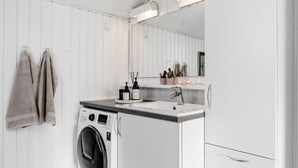 Een moderne badkamer met een wasmachine, wastafel en spiegel.