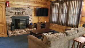 Een gezellige woonkamer met een open haard, een flatscreen televisie en een comfortabele bank.