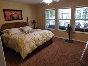 Un dormitorio con cama, ventilador y ventana con vista a muebles de exterior.