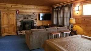 Een blokhutkamer met een open haard, een televisie, een bank en een bed.