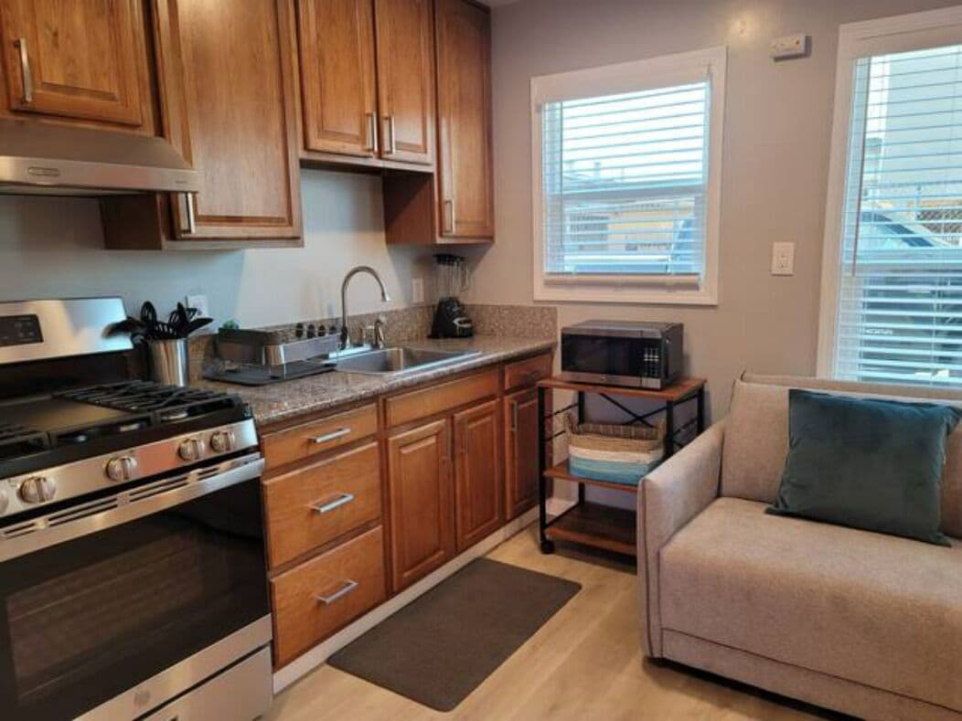 A compact kitchen with wooden cabinets, a stove, and a microwave.